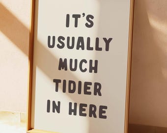 Peut inclure: Une impression encadrée avec le texte "It's usually much tidier in here" en lettres noires en gras sur un fond crème.