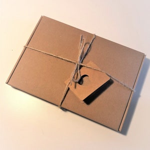 May include: A brown cardboard box with a twine bow and a brown paper tag with a heart cut out. The box is wrapped in brown paper and tied with twine.