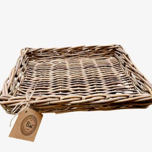 Può includere: Vassoio rettangolare in vimini intrecciato di colore marrone naturale. Il vassoio presenta un motivo intrecciato e un'etichetta attaccata con uno spago. L'etichetta riporta il testo "B" e "HOME ACCESSORIES".