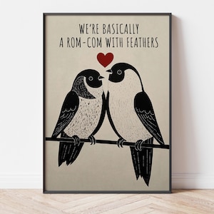 Pode incluir: Uma impressão artística emoldurada com dois pássaros estilizados em preto e branco empoleirados em um galho. Acima, o texto diz "WE'RE BASICALLY A ROM-COM WITH FEATHERS", com um coração vermelho. O fundo é bege.