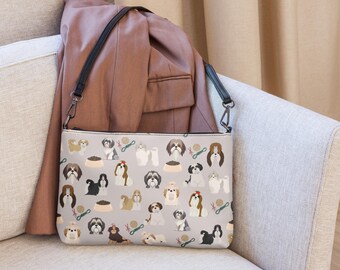 Könnte beinhalten: Eine graue Stoffhandtasche mit einem schwarzen verstellbaren Trageriemen. Die Tasche hat ein sich wiederholendes Muster aus Shih Tzu Hunden in verschiedenen Posen und Farben.