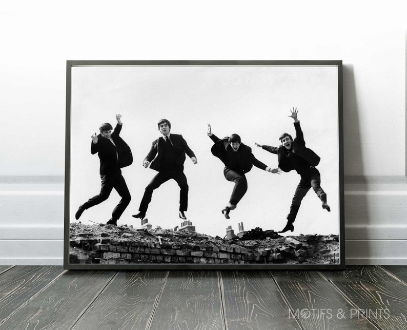 May include: Black and white photograph of four men jumping in the air. The men are wearing suits and are all looking in different directions. The photo is taken from a low angle, and the men are silhouetted against a white background.