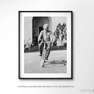 May include: A black and white photograph of Albert Einstein riding a bicycle. He is wearing a light-colored sweater and pants. The photo was taken outdoors.