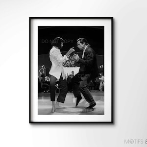May include: Black and white photograph of a man and woman dancing in a nightclub. The man is wearing a suit and the woman is wearing a white shirt and black trousers. The couple are in the centre of the image, with other people dancing in the background.