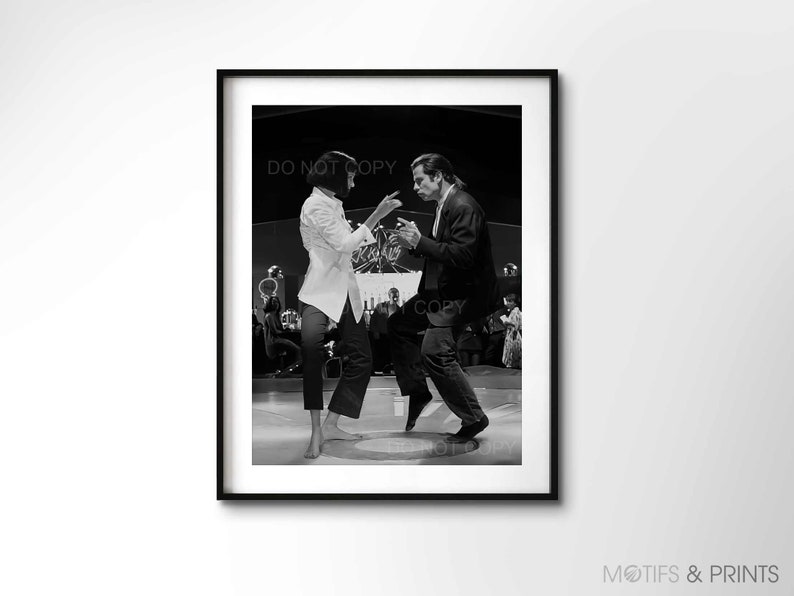 May include: Black and white photograph of a man and woman dancing in a nightclub. The man is wearing a suit and the woman is wearing a white shirt and black trousers. The couple are in the centre of the image, with other people dancing in the background.