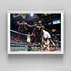 May include: A basketball player in a black and red jersey with the number 3 and the word "HEAT" on the front jumps to dunk the ball. The player is wearing black shorts and black sneakers. The player is in mid-air with his arms outstretched. The background is a basketball court with a crowd of people in the stands.