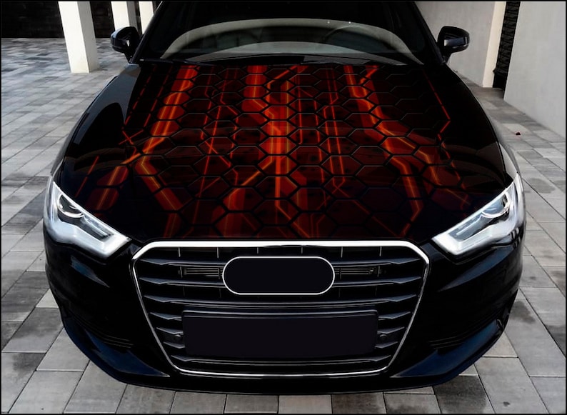 Pu&ograve; includere: Un'auto nera con un design personalizzato del cofano con un motivo a nido d'ape rosso e arancione. La griglia anteriore e i fari dell'auto sono visibili, mostrando un design elegante e moderno. Il design del cofano aggiunge un elemento unico e accattivante.