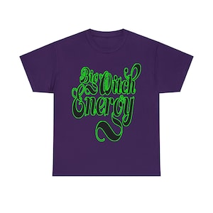 Może przedstawiać: Fioletowy T-shirt z krótkim rękawem z napisem "Big Witch Energy" w czarnych i zielonych literach.