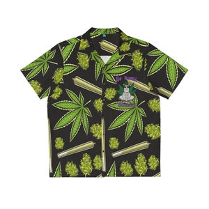 Puede incluir: Una camisa negra de botones con manga corta. La camisa tiene un patrón repetido de hojas verdes de marihuana, cogollos de marihuana y porros de marihuana enrollados. La camisa tiene un gráfico de una llama sentada en una postura meditativa con el texto "No Drama Llama" arriba.