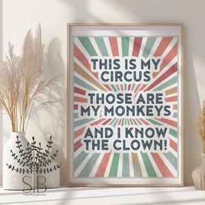 May include: Framed art print with the text "THIS IS MY CIRCUS, THOSE ARE MY MONKEYS, AND I KNOW THE CLOWN!" in a retro circus-themed design. The background features a burst of red, green, and yellow rays. The print is in a light wood frame.