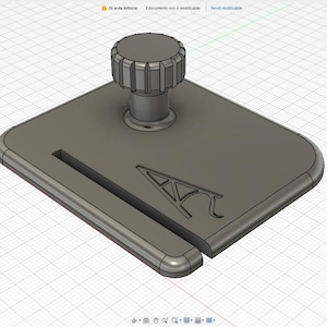 May include: A gray, 3D-printed object with a square base and a cylindrical knob. The base has a slot and a stylized letter "A" design. The knob is ridged for grip.