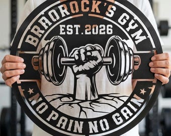May include: A circular black metal wall sign featuring a cutout design of a fist holding a dumbbell. The text reads "BRADROCK'S GYM", "EST.2026", and "NO PAIN NO GAIN". The design includes copper-colored accents and a cracked ground graphic.