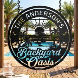 May include: Black metal sign with the text "THE ANDERSON'S Backyard Oasis" in a circular design. The sign features a sunset, palm trees, and cocktail glasses. The sign is hanging with chains.