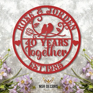 Puede incluir: Un letrero de metal rojo con el texto "Rose & Jordan 40 Years Together Est 1985" y dos p&aacute;jaros en una rama con hojas.