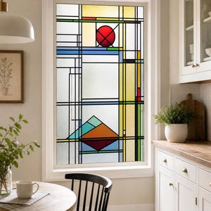 Puede incluir: Una película rectangular para ventana con un patrón geométrico de vidrieras y líneas de plomo negras. El diseño incluye un círculo rojo prominente, paneles amarillos y una sección inferior con formas triangulares azules, turquesas y naranjas sobre vidrio esmerilado.