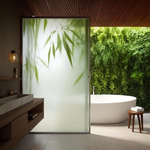 Puede incluir: Un baño moderno con una mampara de ducha de vidrio esmerilado con un diseño de hojas de bambú. La habitación incluye un tocador de madera con un lavabo de piedra, una bañera blanca y una pared vegetal de plantas verdes. Un pequeño taburete de madera sostiene toallas blancas enrolladas.