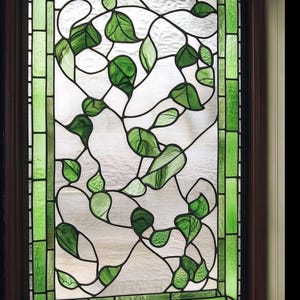 May include: A stained glass window with a design of green leaves and vines. The window is framed in wood and has a green border.