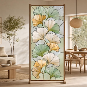 Könnte beinhalten: Ein hoher, rechteckiger Raumteiler mit einem Buntglas-Paneel, das ein Ginkgo-Blatt-Muster zeigt. Das Design besteht aus überlappenden, fächerförmigen Blättern in blassem Grün, Creme und sanftem Gelb, umrandet von dunklen, feinen Linien.