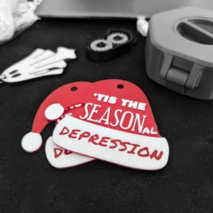 May include: Red and white felt Christmas ornament shaped like a Santa hat with the text "'Tis the Season" and "Depression" on it.