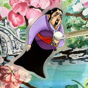 May include: A sticker of a woman with dark hair and a purple robe holding a white teapot. She has a dark expression on her face and dark streaks on her face.