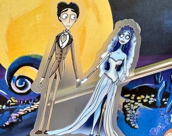 May include: A clear sticker featuring a cartoon couple from the movie "Corpse Bride". The groom wears a brown suit, and the bride is in a white wedding dress with blue skin and hair. They are holding hands against a background of a moon and dark blue imagery.