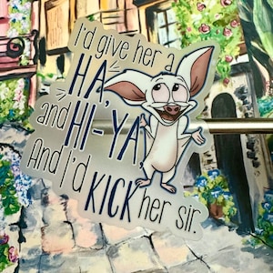 以下が含まれることがあります： 大きな目と笑顔の白い漫画のこうもり。こうもりは白いシャツを着ていて、腕を広げています。「I'd give her a HA and HI-YA! And I'd kick her sir.」というテキストが、こうもりの周りに青と黒で書かれています。