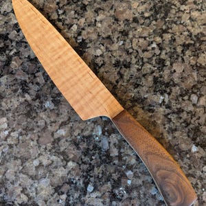 May include: A wooden kitchen knife with a maple wood blade and a walnut wood handle.