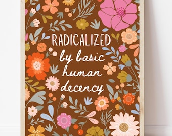 May include: A framed art print with a brown background and a floral design. The print features the words "RADICALIZED by basic human decency" in white script. The flowers are in shades of pink, orange, and yellow.