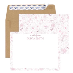 May include: A white note card with a pink floral border. The card has the text 'a note from' and 'OLIVIA SMITH' printed in pink. The card is displayed with a brown envelope.