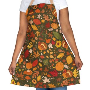 May include: A green apron with a Thanksgiving-themed print featuring turkeys, pumpkins, leaves, and acorns.