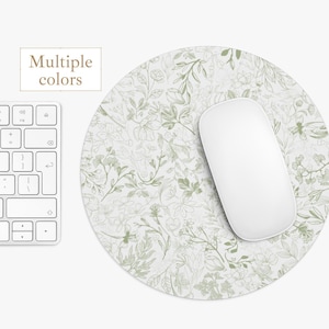 May include: A round mousepad with a floral pattern in shades of green and white. A white wireless mouse rests on the pad. A white keyboard is partially visible in the image. The text "Multiple colors" is in the upper left corner.