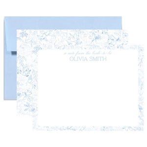 May include: A light blue stationery set featuring a floral design. The set includes a blank card with the text "a note from the bride to be OLIVIA SMITH" and a matching envelope. The card has a floral border.
