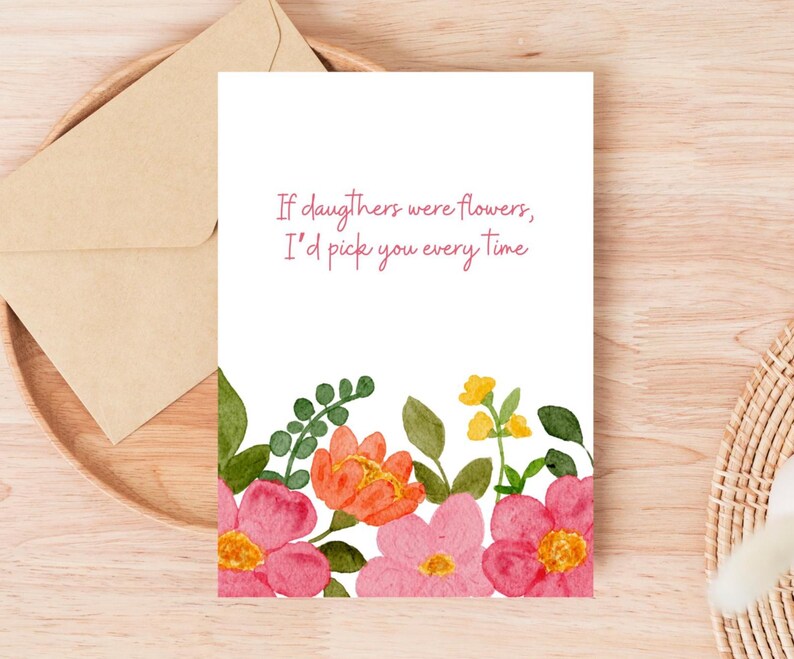 Peut inclure: Une carte de v&oelig;ux blanche avec le texte "If daughters were flowers, I'd pick you every time." La carte pr&eacute;sente des fleurs &agrave; l'aquarelle roses, oranges et jaunes. Une enveloppe repose sur un plateau en bois.