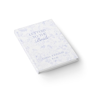 May include: A white book titled "Letters to the Bride" with a blue floral pattern. The bride's name and wedding date are printed at the bottom. The book is angled slightly, showing its cover and spine.