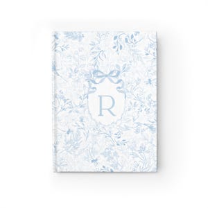 May include: A blue and white floral patterned journal with a white monogrammed initial "R" in a blue ribbon bow.