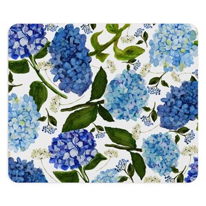 K&ouml;nnte beinhalten: Ein wei&szlig;er Hintergrund mit einem sich wiederholenden Muster aus blauen Hortensienbl&uuml;ten und gr&uuml;nen Bl&auml;ttern.