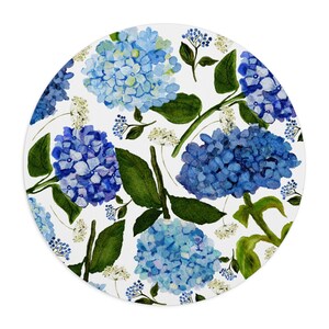 K&ouml;nnte beinhalten: Ein runder, wei&szlig;er Hintergrund mit einem sich wiederholenden Muster aus blauen Hortensienbl&uuml;ten und gr&uuml;nen Bl&auml;ttern. Die Blumen sind in Aquarell gemalt und haben ein weiches, romantisches Flair.