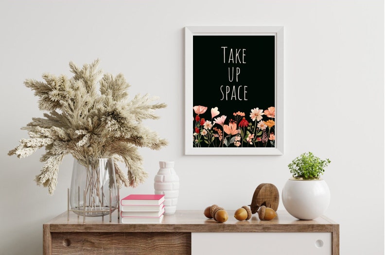 May include: A black and white printable wall art print with the text "TAKE UP SPACE" in white lettering. The print features a floral border of pink, orange, and red flowers on a black background.