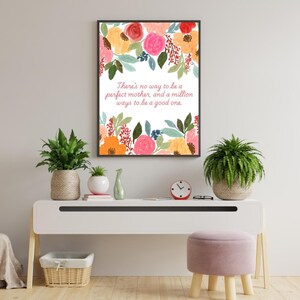 May include: A framed print with a white background and colourful floral illustrations. The text reads "There's no way to be a perfect mother, and a million ways to be a good one."