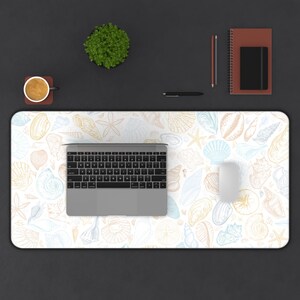 May include: A white desk mat with a light blue and yellow seashell pattern. A laptop computer and a white mouse are on the desk mat.