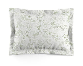 May include: A rectangular pillowcase with a white background and a delicate pattern of green leaves and floral elements. The pillowcase has a soft, muted color palette, creating a calming and natural aesthetic. The design is evenly distributed across the fabric.