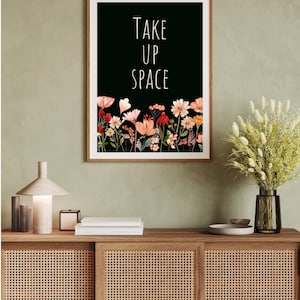 May include: A black and white print with the text "TAKE UP SPACE" in white lettering. The print features a border of colorful flowers on a black background.