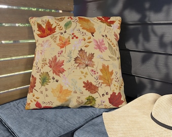 May include: A throw pillow with a autumn-themed design featuring a pattern of colourful autumn leaves on a cream background.