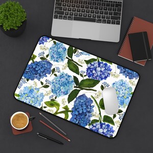 May include: A white mouse pad with a blue and green floral pattern. The pattern features hydrangeas and leaves.
