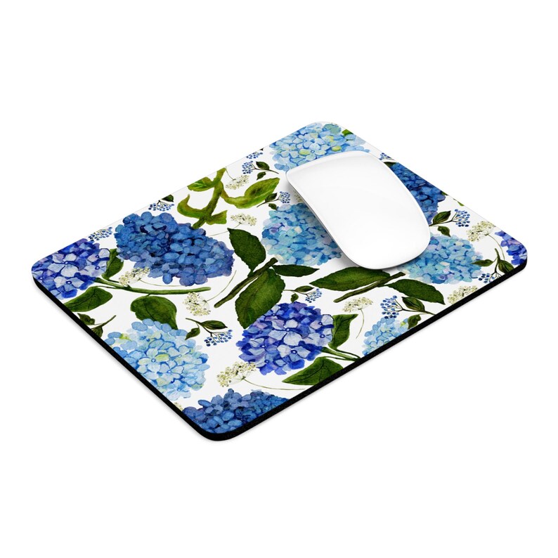 K&ouml;nnte beinhalten: Ein wei&szlig;es Mauspad mit einem blauen und wei&szlig;en Blumenmuster. Das Muster zeigt blaue Hortensien und wei&szlig;e Bl&uuml;ten auf wei&szlig;em Hintergrund.