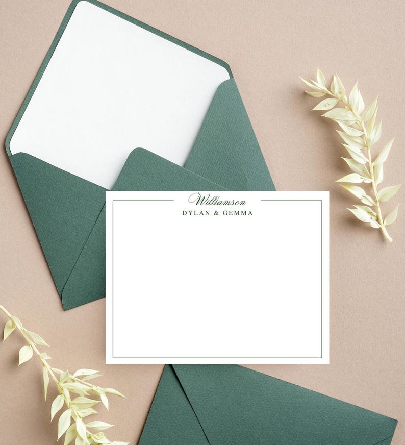 May include: A stationery set featuring a white card with a dark green border and the names "Williamson, Dylan & Gemma" printed in dark green. The card is surrounded by dark green envelopes and decorative sprigs on a tan surface.