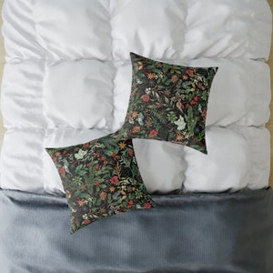 May include: Two decorative throw pillows with a dark green background and a floral pattern featuring red berries, green leaves, and gold accents.