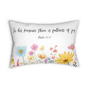 Puede incluir: Almohada blanca con diseño floral y la cita "En su presencia hay plenitud de alegría - Salmo 16:11"
