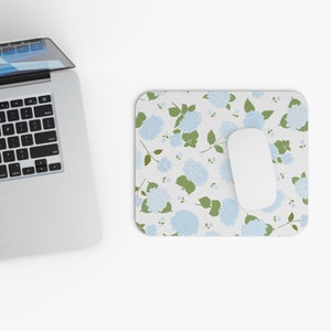May include: A white computer mouse sits on a white and blue floral mousepad with a light blue hydrangea pattern.