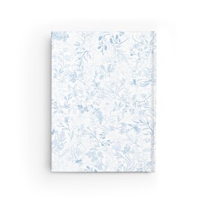 May include: A blue and white floral pattern on a notebook cover. The pattern is a delicate design of leaves and flowers.